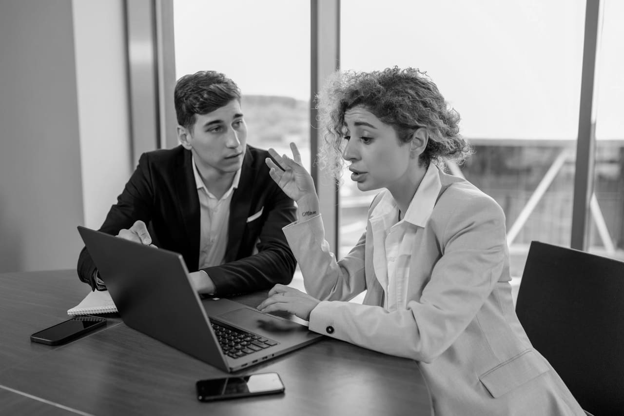 Two people reviewing documents across a table in a modern office